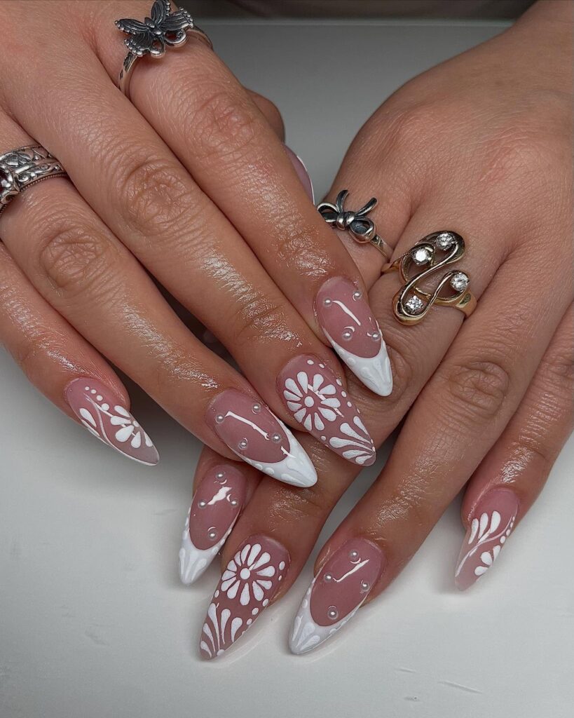 Almond-Shaped Nude-Pink Nails with White Daisy Flowers, Leaf Patterns, and Pearl Embellishments for a Floral Graduation Style