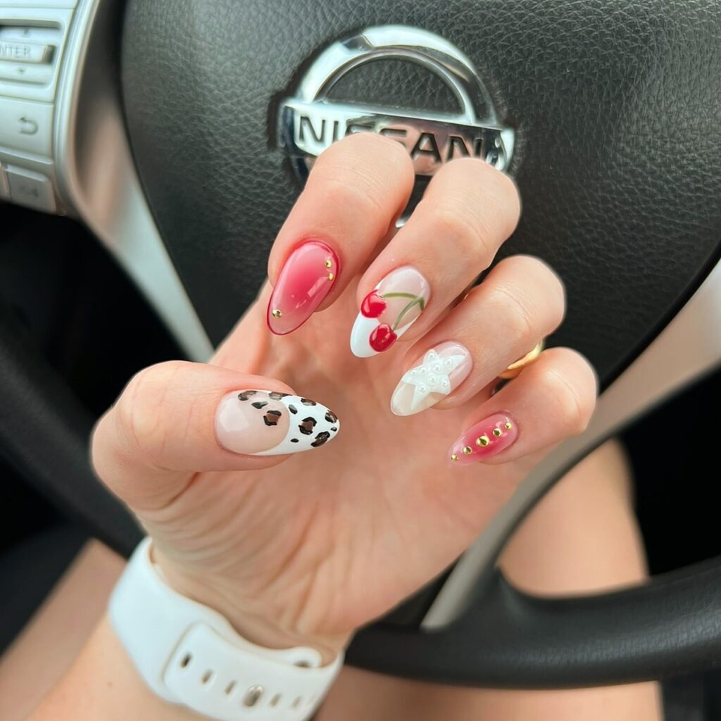 Almond Birthday Nails with Nude, White, and Pink Base Featuring Hand-Painted Red Cherries, 3D Bows, Gold Studs, and Animal Print
