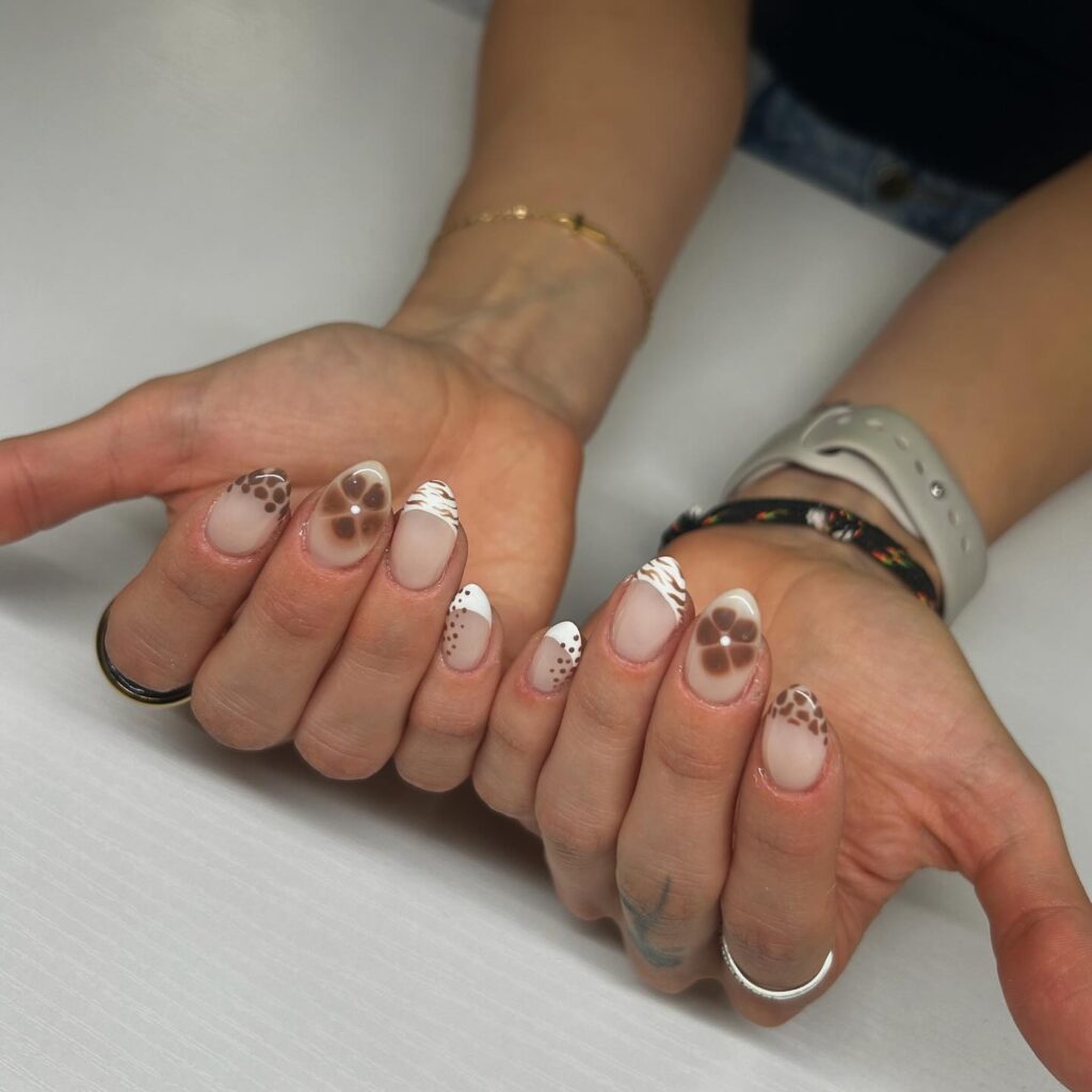 Almond matte nude nails with chocolate brown swirls and floral patterns for a cozy fall look