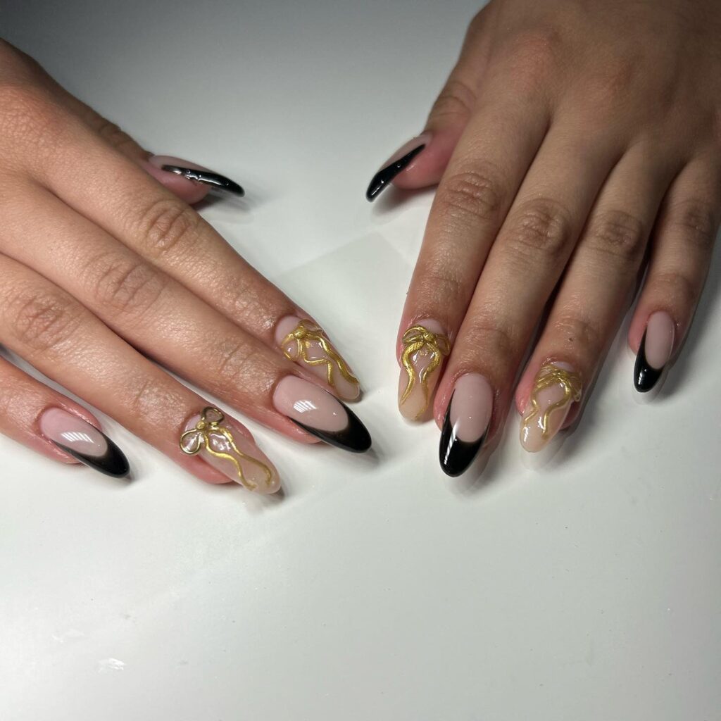 Almond nude and black french tips with gold details – glam graduation nail art ideas