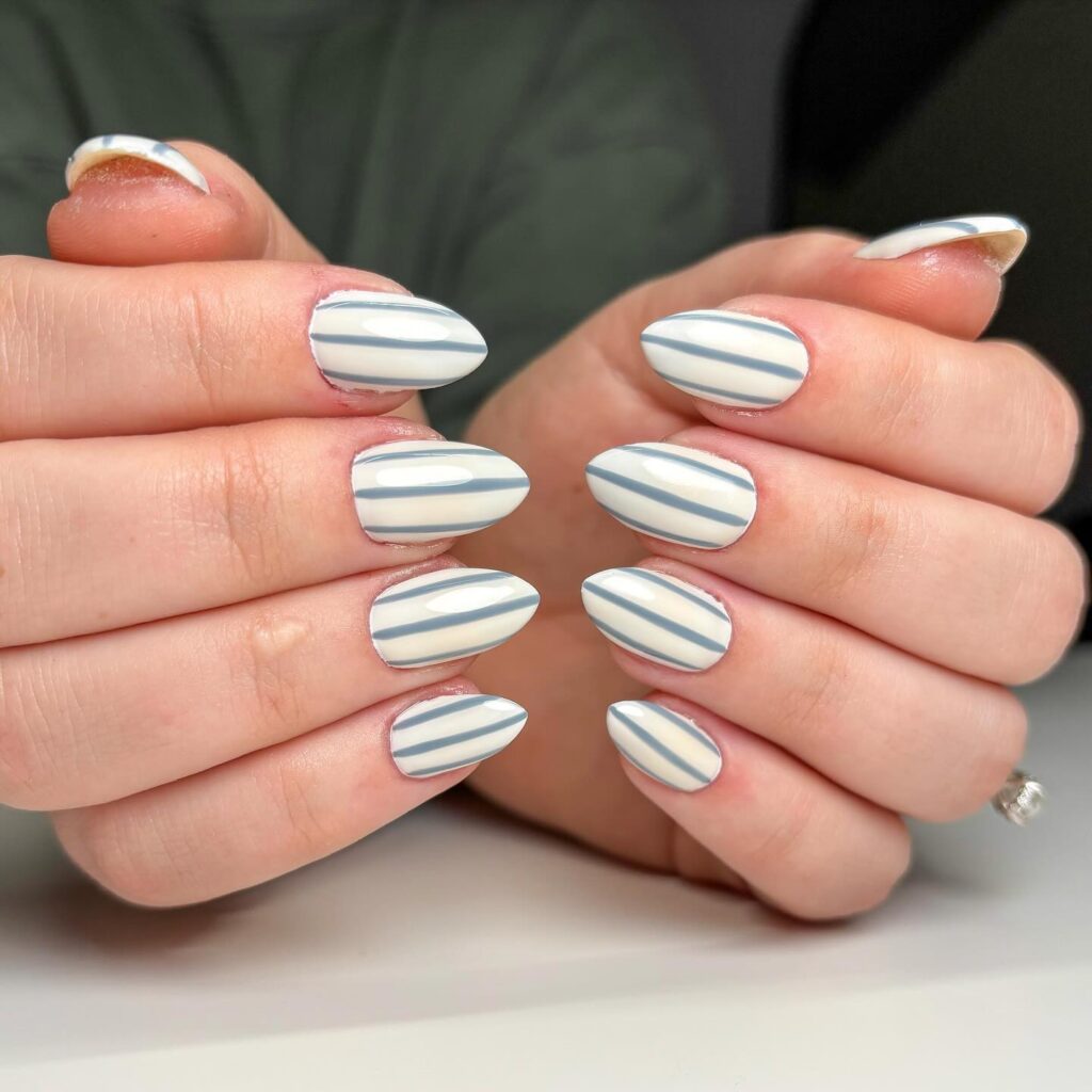 Almond shaped nautical nails with white and muted blue stripes for a chic summer statement