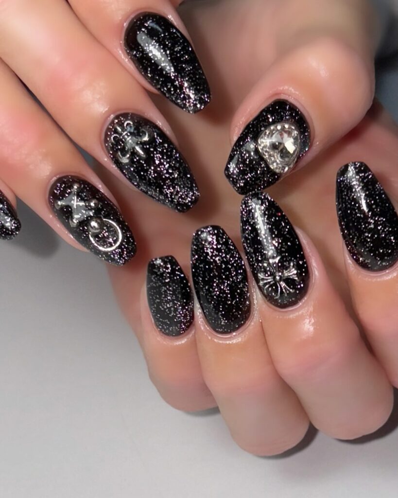 Black Glitter Nails with 3D Metallic Charms – Celestial Nail Idea for a Gothic Luxe Statement Look