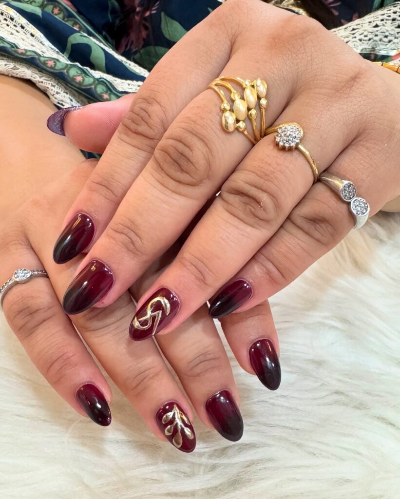 Burgundy to Black Almond Nails with Gold Leafy Designs for an Elegant Ombré Look