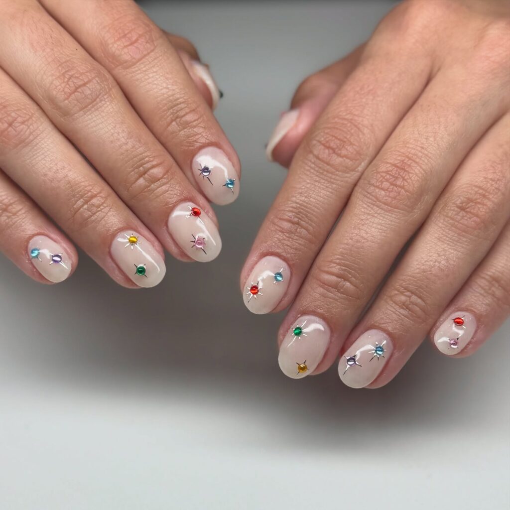 Colorful Gem-Embellished Nude Nails with a Subtle Starburst Effect
