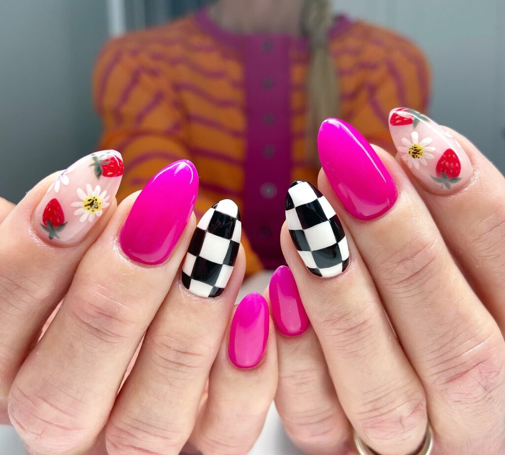 Hot pink almond nails with strawberry daisy art and checkerboard patterns for a fun summer nail idea