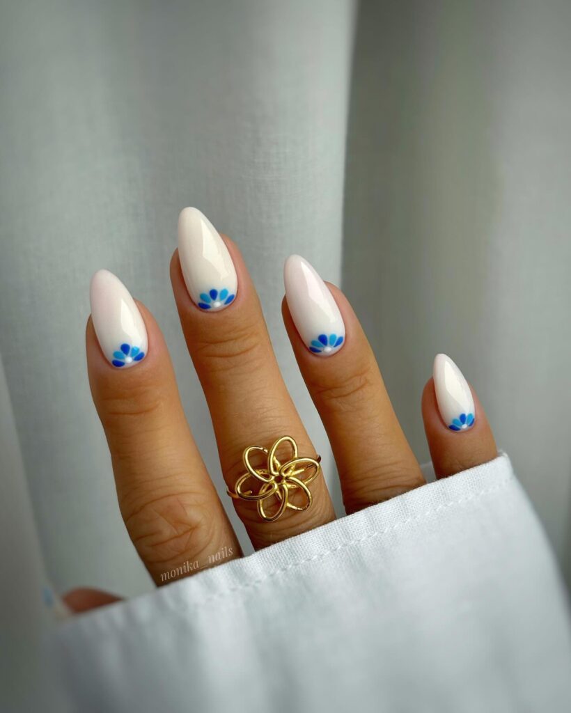 Milky Almond Nails with Tiny Blue Floral Accents for a Spring Garden Look