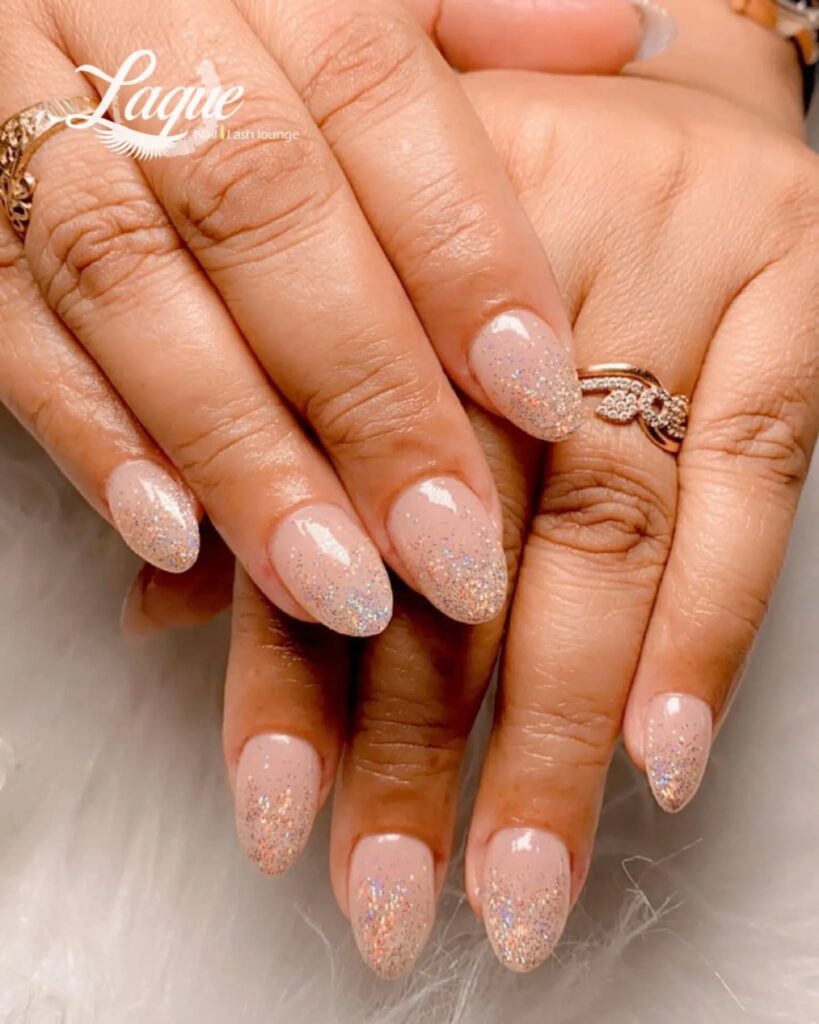 Nude almond nails with iridescent glitter fade soft glam nail ideas for special occasions