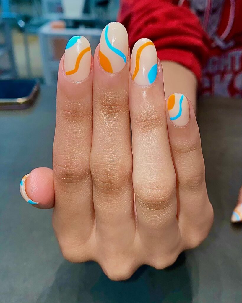 Oval Nude Nails with Bright Orange and Blue Swirl Patterns for a Playful Graduation Look