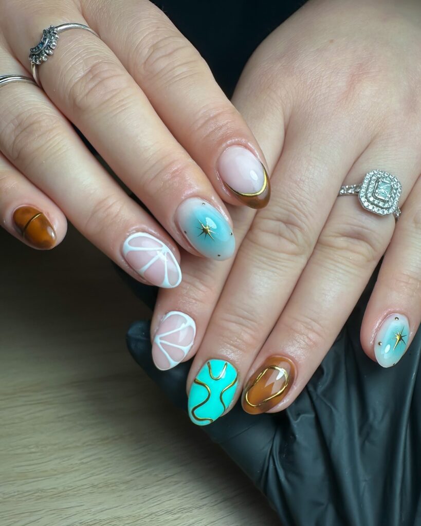 Short oval nails in caramel mint and sky blue with starburst and abstract designs for a creative colorful style