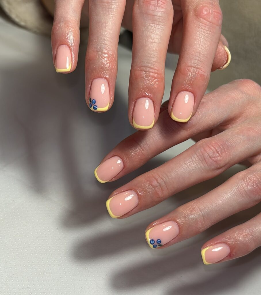 Soft square nude nails with yellow french tips and blue rhinestones spring nail ideas