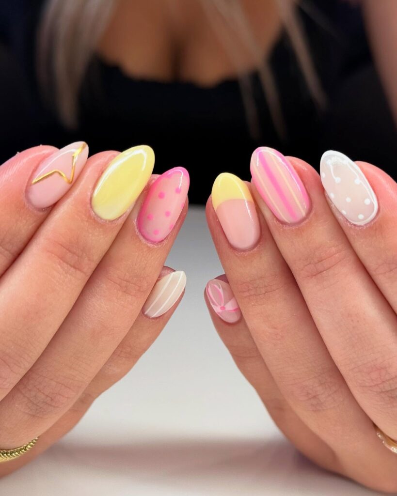 Whimsical pastel almond nails with polka dots stripes and abstract art for a creative spring and summer nail look