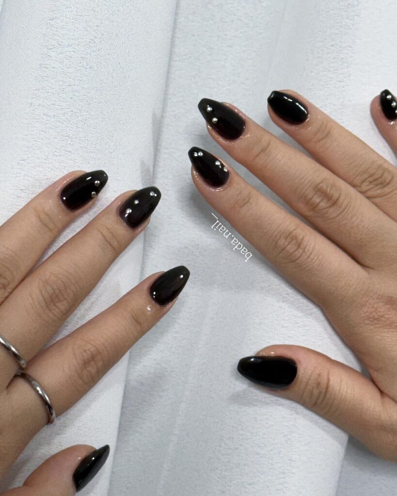 Black almond nails with silver stud accents for a minimalist glam nail look