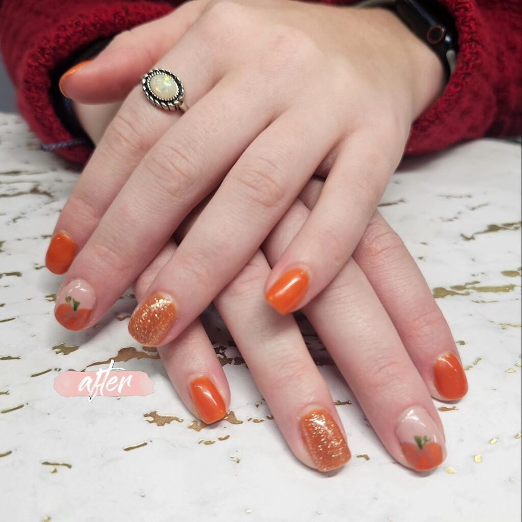 Burnt orange short nails with pumpkins and glitter for a cozy fall graduation idea