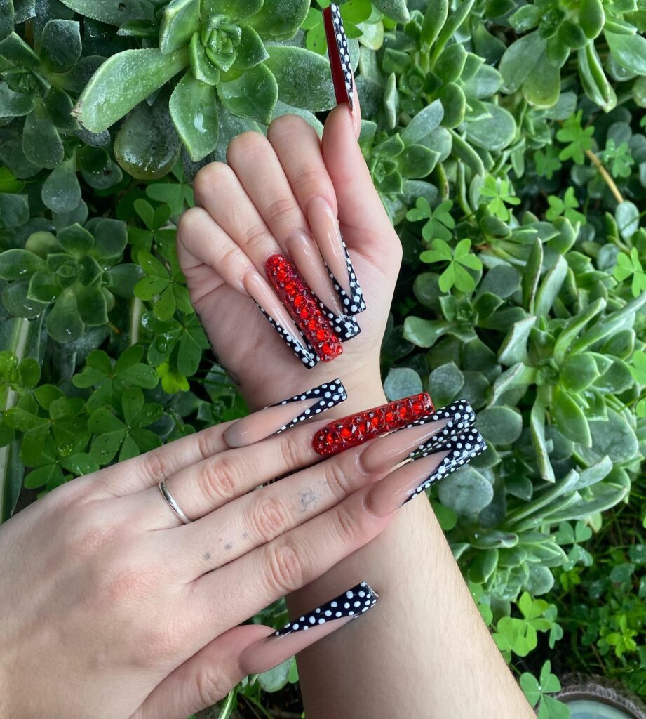 Coffin nude nails with red rhinestones and retro polka dots for graduation sparkle
