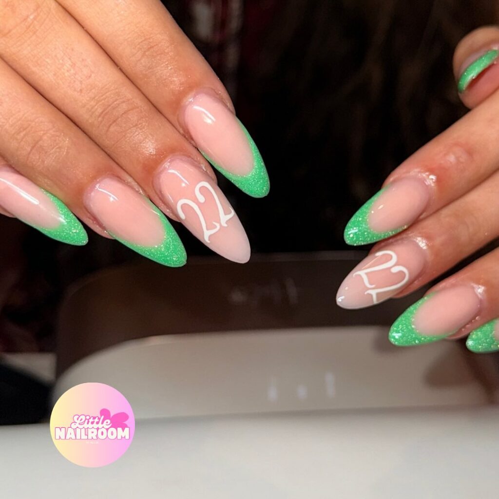 Green Glitter French Tips and '22' Accents on Almond Nails for a Fresh Birthday Twist