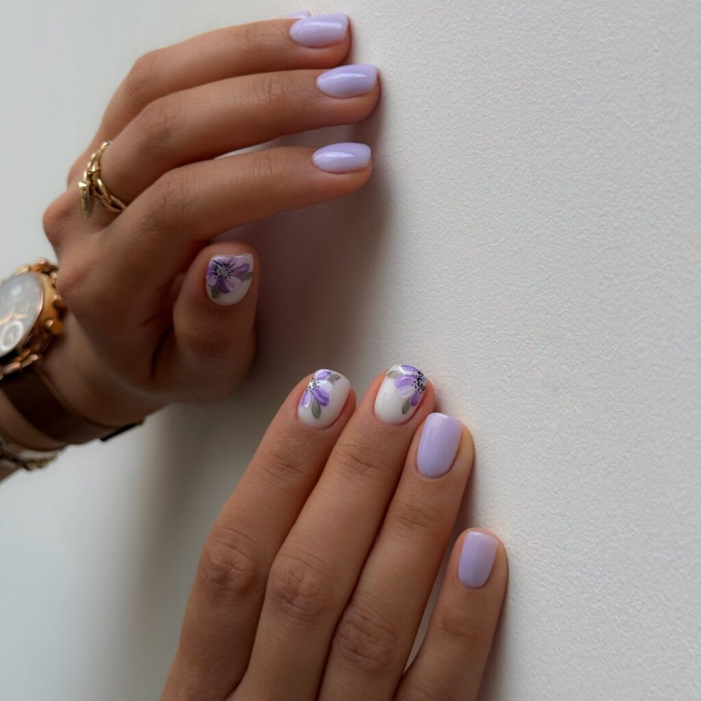 Lavender floral short nails with hand painted purple blooms and soft nude accents for spring nail inspiration