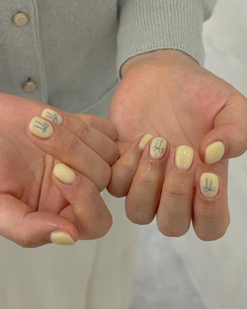 Pastel yellow nails with bunny face accents for spring Easter nail inspiration
