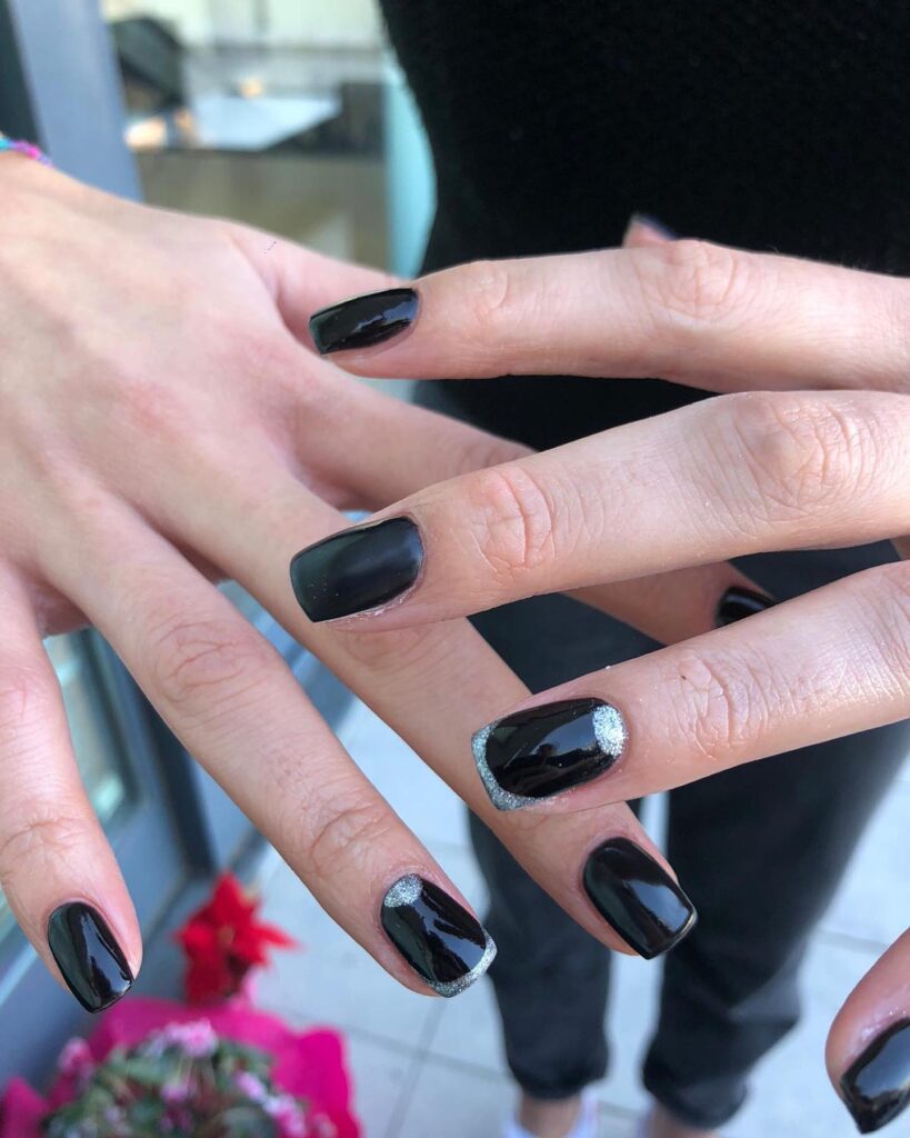 Short square black nails with silver glitter accents and half-moon design for a festive and classy look