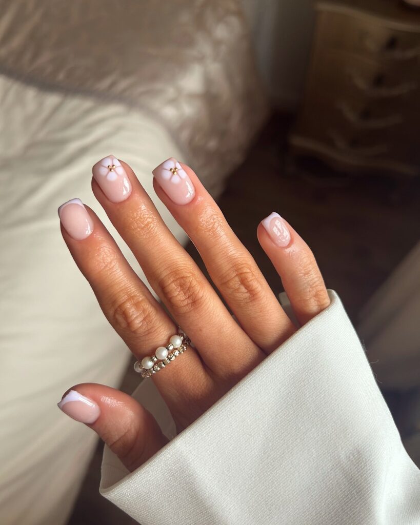 Short square nails with diagonal French tips and tiny flower accents elegant nail ideas