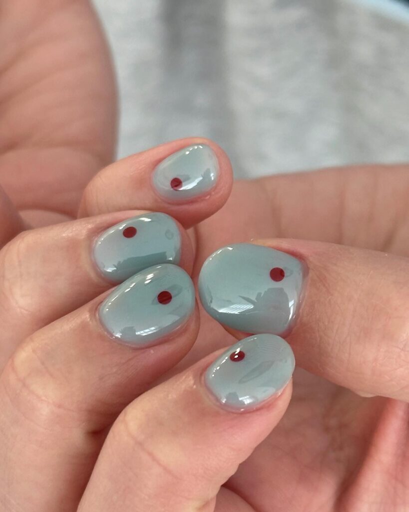 Soft blue grey short nails with single red dot accents for minimalist modern short nail design ideas