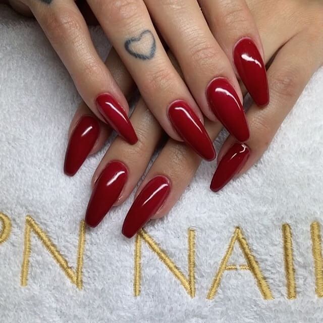 Stiletto Red Nails with Tattoo Accents for a Bold Glam Vibe