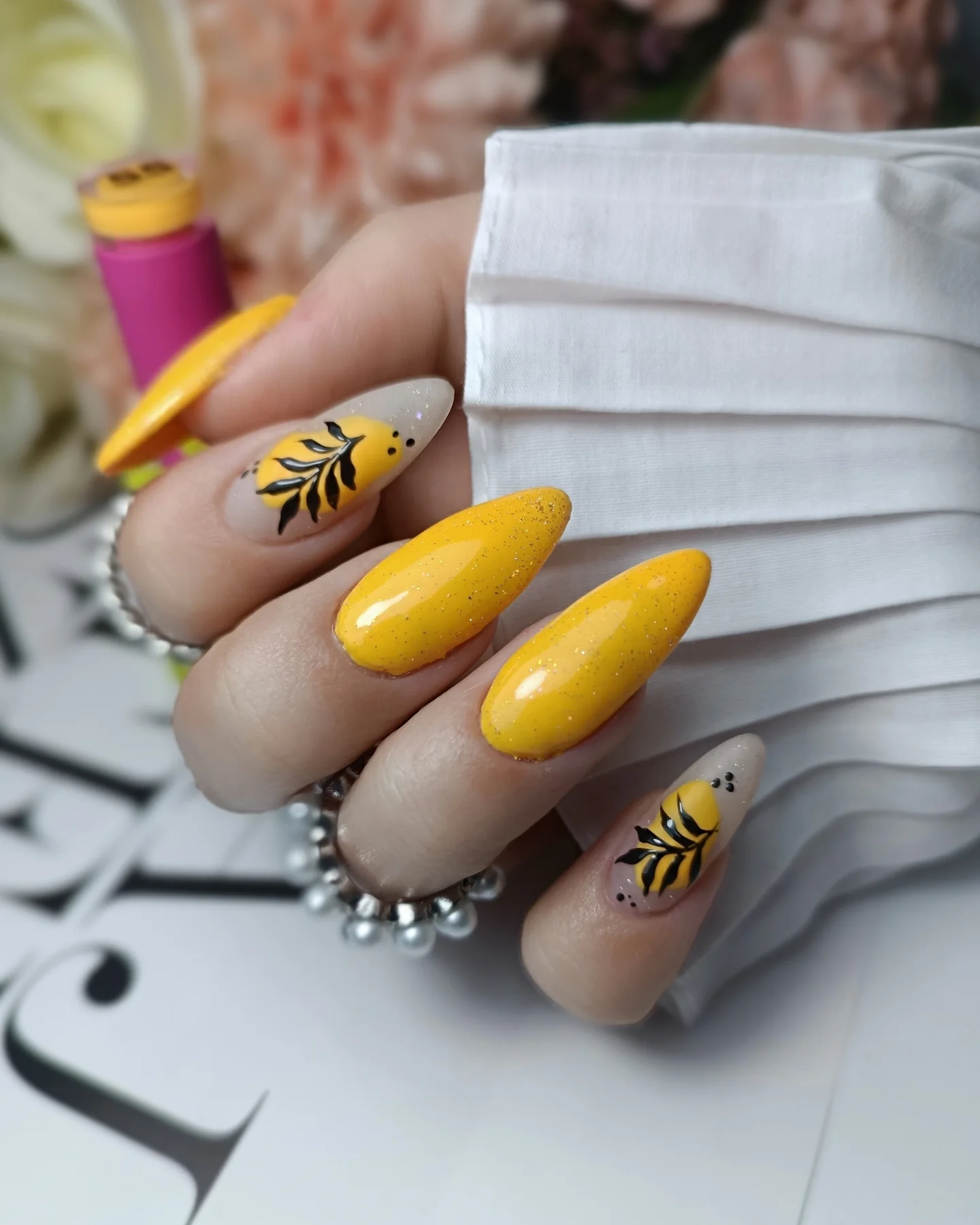 Vibrant Yellow Glitter Almond Nails with Hand-Painted Leaf Designs for Nature-Inspired Nail Ideas